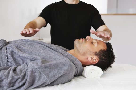 A man laying on a couch receiving reiki